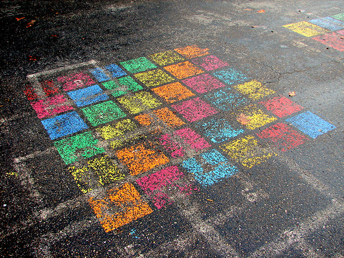 A picture of a mult-colored cube made of cubes on the pavement at a playground