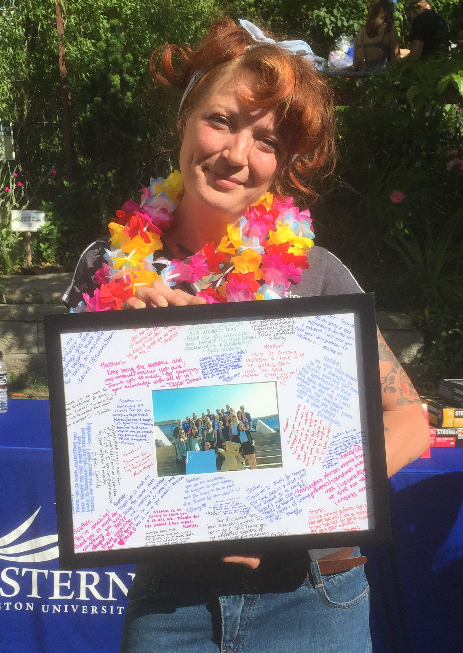 Holding a framed and signed picture of the students with the stuffed bear.