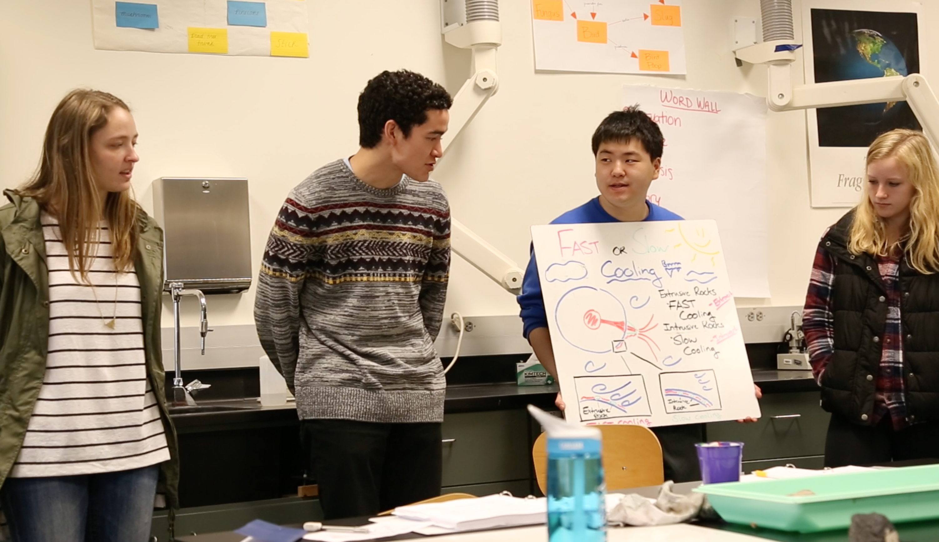 Another group of students presenting their work on a whiteboard at the front of the class
