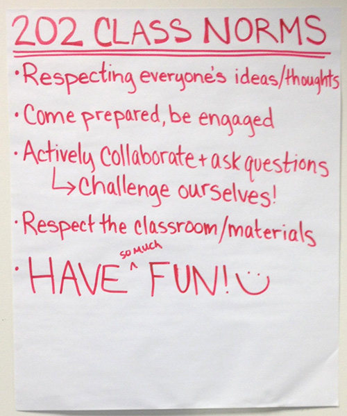 Students at a table writing answers on a mini whiteboard