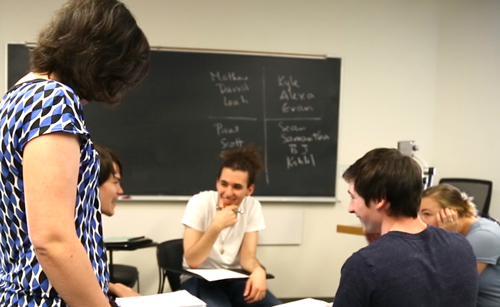Dr. Treneer gives feedback to a group as they work together in class
