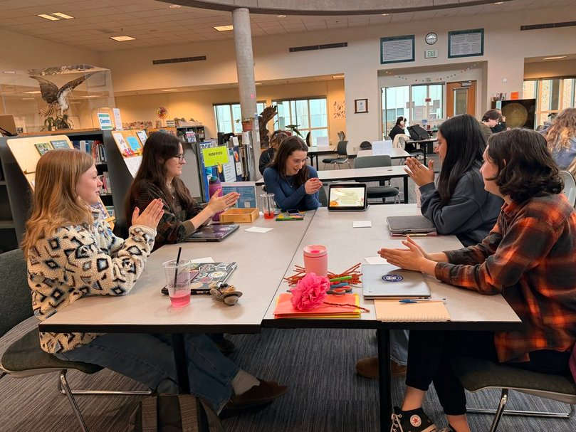 Students engaged in small group discussion around a table in a classroom