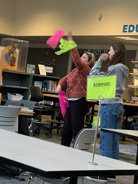 Students participating in an interactive microteaching activity, with one student tossing colorful items to engage the class