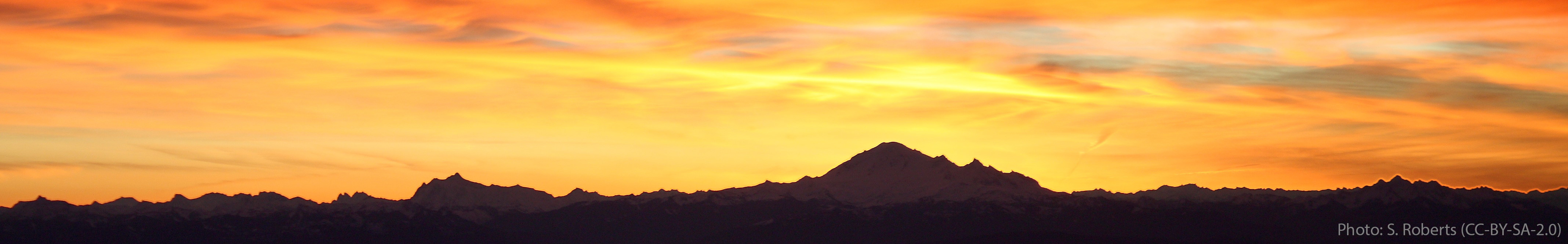 A shadowy silhouette of a mountain peak against an orange sky